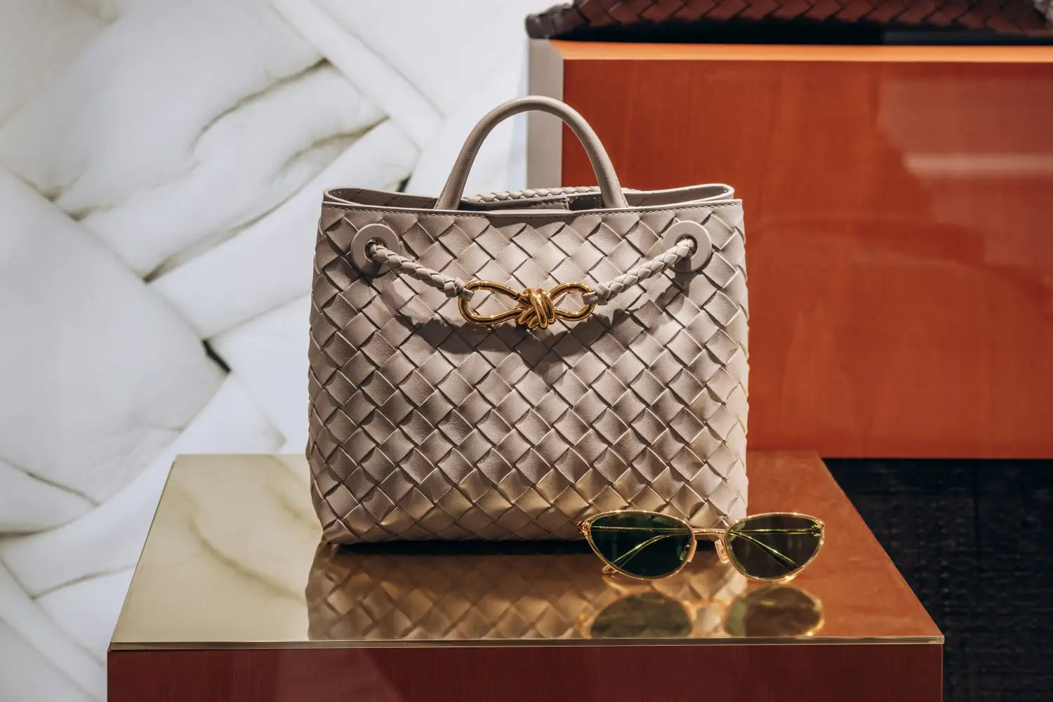 Beige woven leather handbag with gold hardware and braided handles