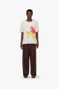 White short-sleeved t-shirt with pink rose graphic and red trim paired with adidas originals by wales bonner brown recycled track trousers