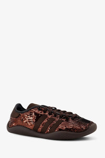 A shimmering rose gold sequined adidas Originals by Wales Bonner women’s nylon sneaker with dark brown leather stripes and laces