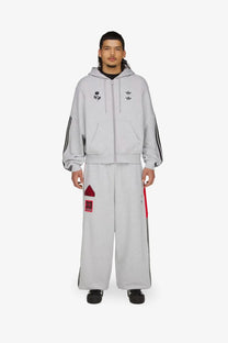 Gray adidas Originals x Willy Chavarria men’s cotton blend tracksuit trousers with black stripes and red accents