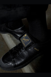 Adidas Originals x Willy Chavarria men’s black leather sneakers with gold branding and willy text on the side