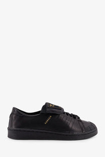 Adidas Originals x Willy Chavarria black leather sneaker with gold branding and classic shell-toe design