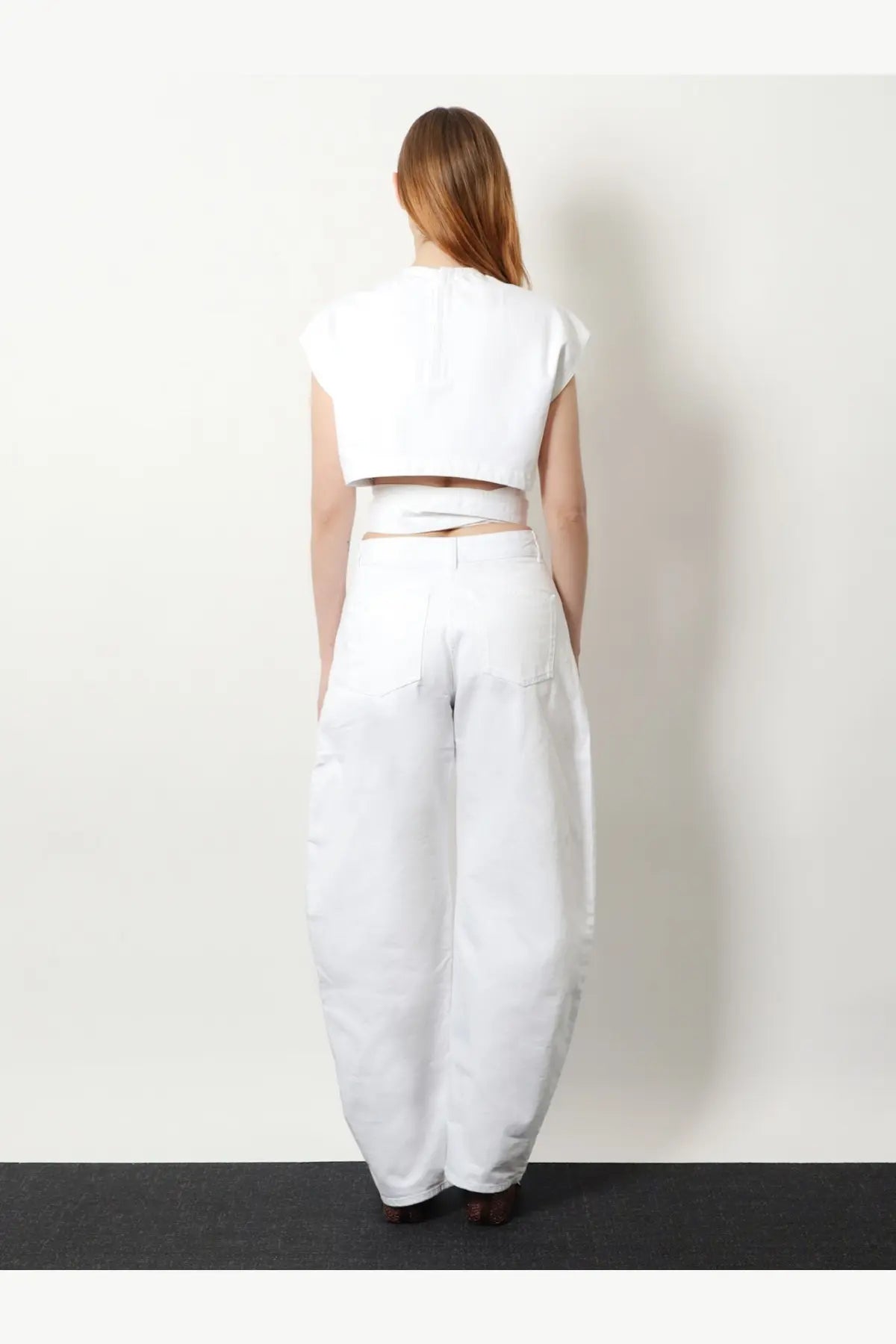 Alaïa women’s white cotton crop fit belted top paired with white wide-leg trousers ensemble front view
