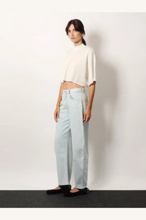 Light blue wide-leg denim pants with a relaxed flowing silhouette paired with a white Alaïa cropped cotton blend top
