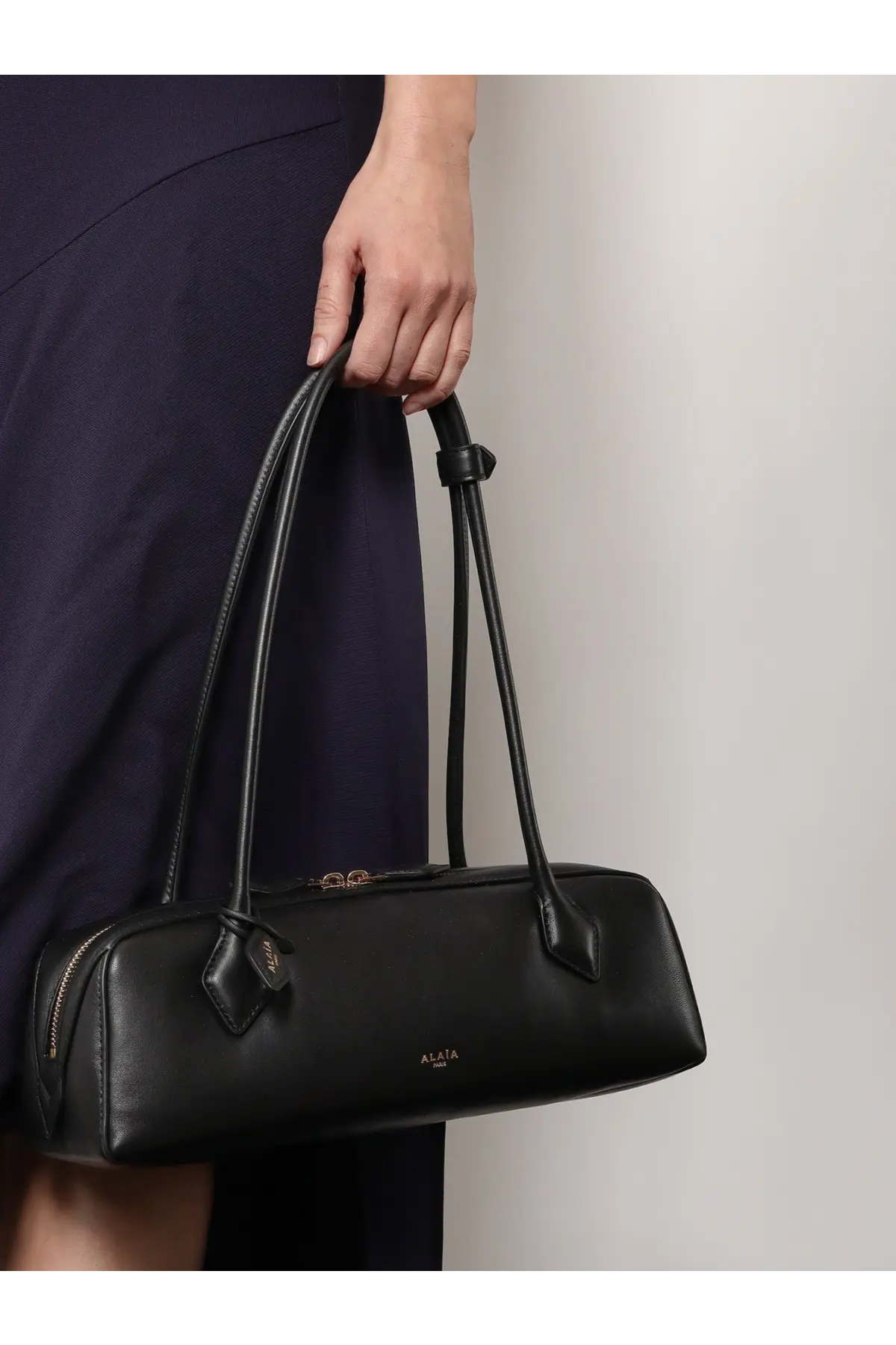Alaïa women’s le teckel black leather handbag with sleek elongated rectangular shape and dual top handles