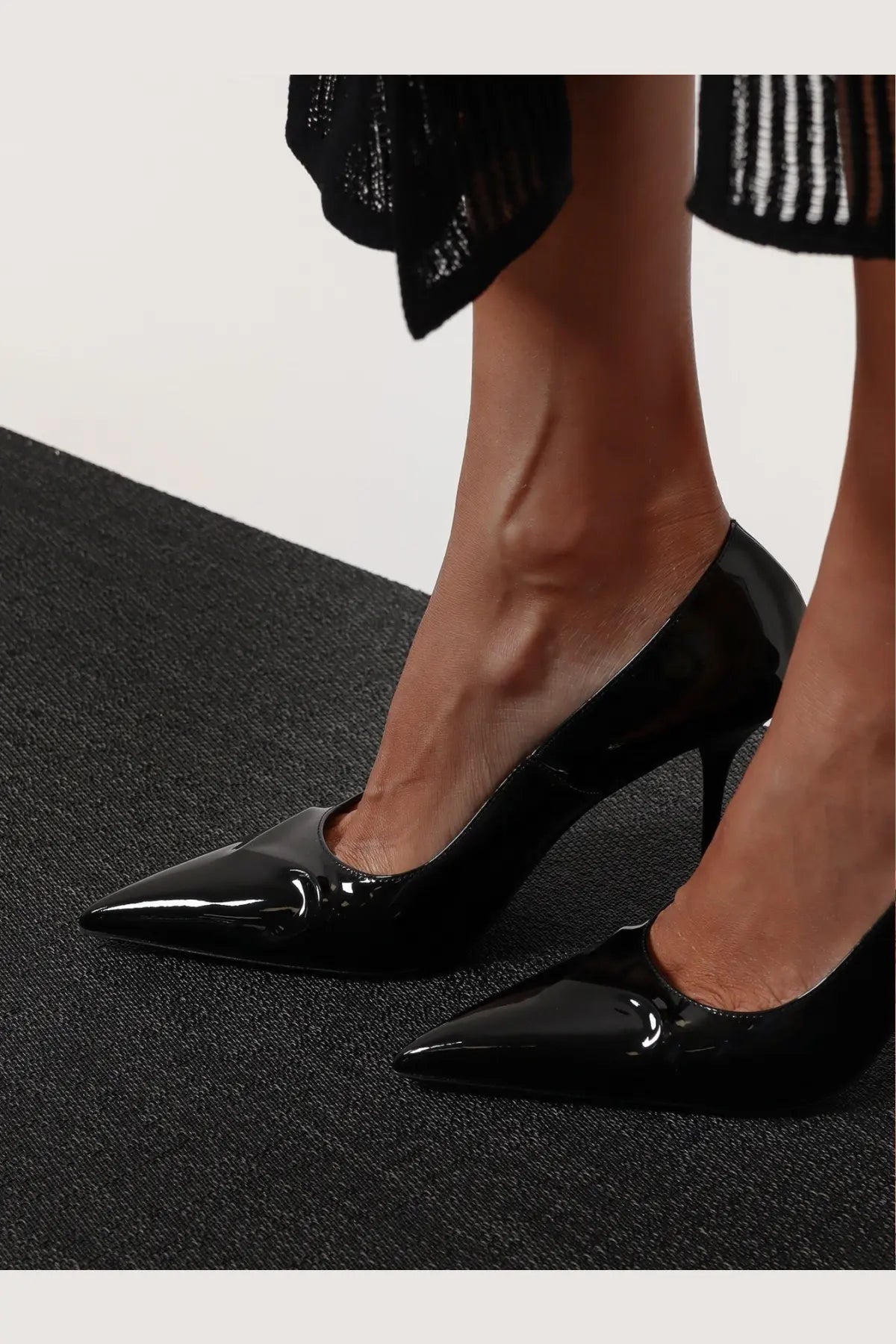 Alaïa women’s black patent leather decolleté pumps with pointed toes and slender heels in a glossy finish
