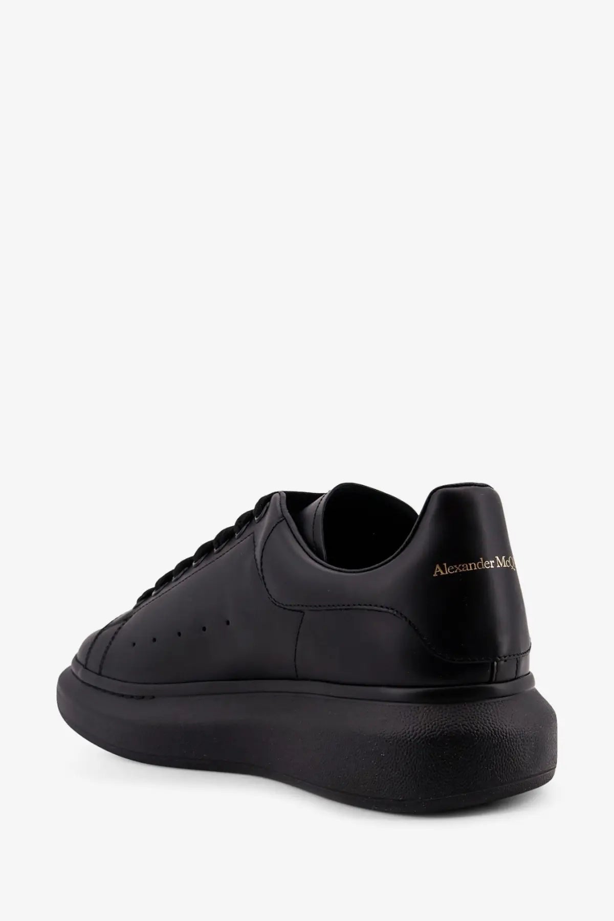 Back view of alexander mcqueen men’s black leather sneaker with chunky sole and gold branding on the heel