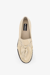 Cream-colored leather loafer with frayed tassel detail and black rubber sole from Alohas women’s Marietta collection