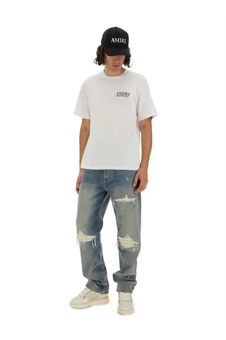 White amiri t shirt with subtle black logo on chest paired with men’s blue mx1 jeans