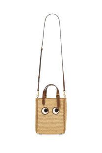 Anya Hindmarch women’s beige woven straw tote bag with brown leather handles and cartoon eyes on front