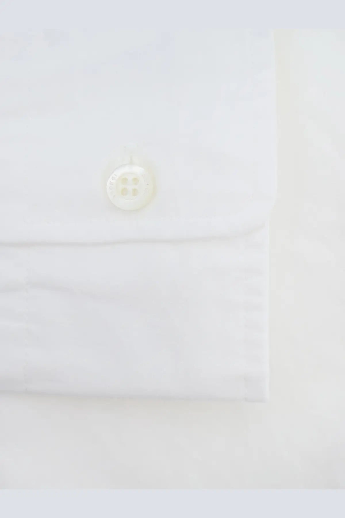 A crisp white cotton ASPESI men’s Fred shirt cuff with a single off-white four-hole button
