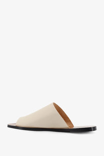 Cream-colored leather slide sandal with black sole and tan lining by ATP Atelier women’s rosa linen sandals