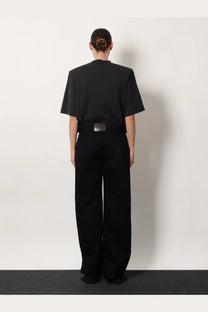 Black oversized short-sleeved top with structured shoulders paired with the attico women’s black denim trousers black