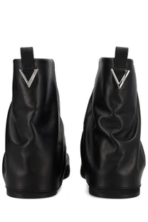 The back side of the attico women’s black leather ankle combat mini robin boot with a glossy finish and silver v logo