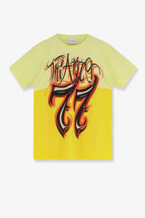 A vibrant yellow cotton short-sleeved t-shirt with black and orange flame lettering reading the alice 77 by The Attico