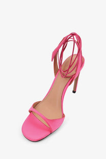 A vibrant pink satin high-heeled sandal with slender heel and intricate ankle straps from The Attico Ora collection