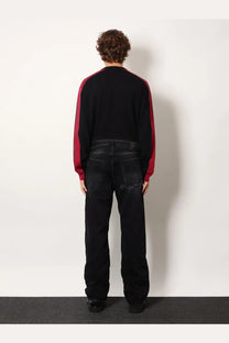 Balenciaga men’s black denim jeans paired with a black sweater featuring bold red sleeves and a classic crew neck