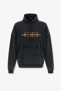 Balenciaga men’s black cotton hoodie with distressed oversized fit and rust-colored logo embroidery on the chest