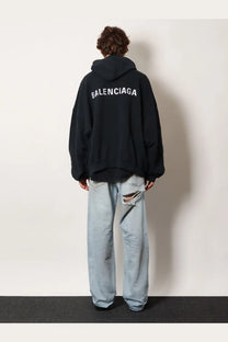 Back view of balenciaga men’s black cotton hooded sweatshirt with white lettering across the back