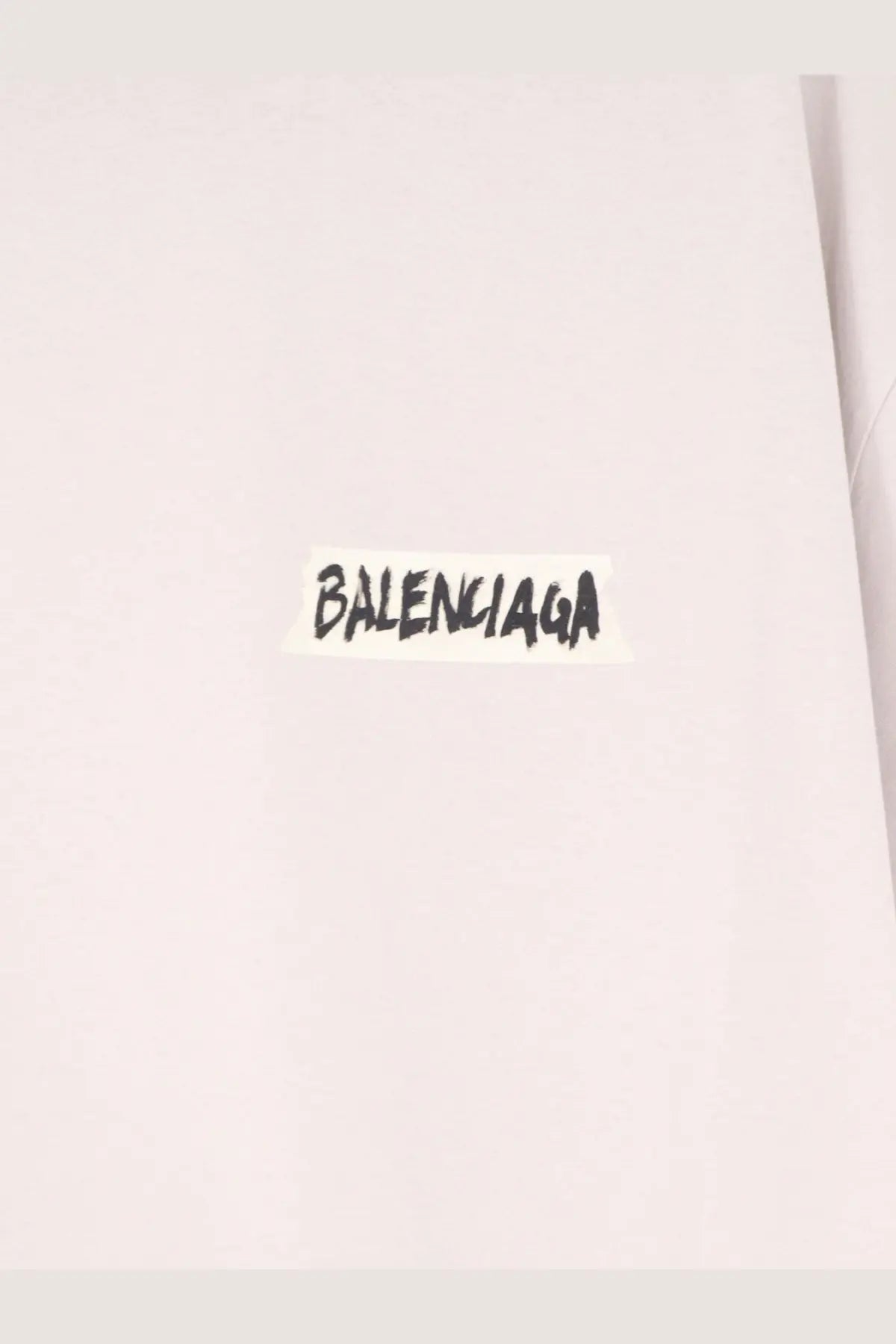 A white balenciaga sticker with black handwritten lettering on a white cotton balenciaga men’s shirt