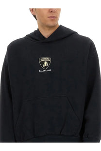 Balenciaga men’s black hoodie featuring a gold-tone lamborghini logo patch on the chest for casual wear