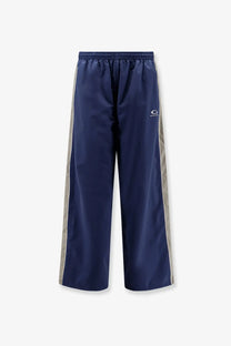 Balenciaga men’s navy blue nylon track pants with silver side stripes and a small white logo on the thigh