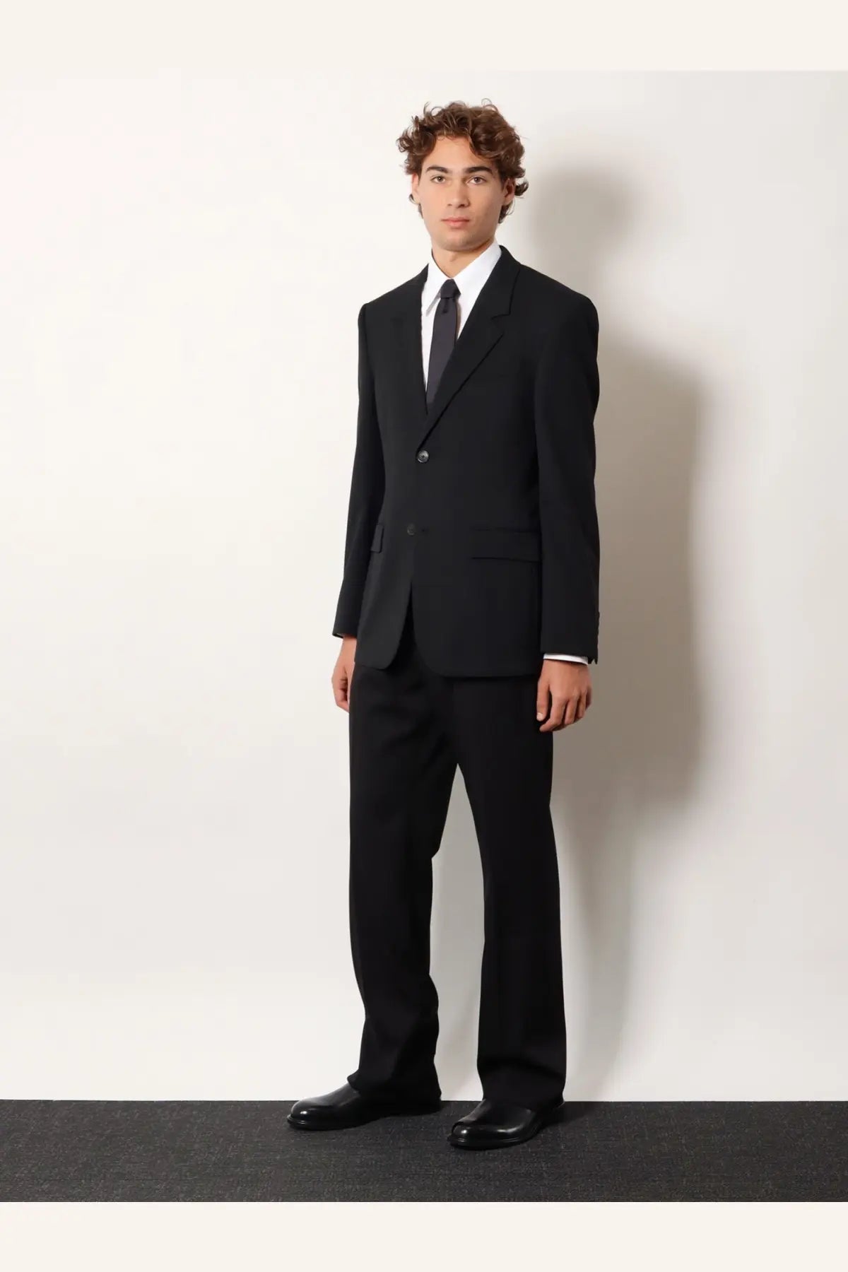 Balenciaga men’s black tailored wool blazer with single-button jacket and matching trousers styled formal with white shirt and tie