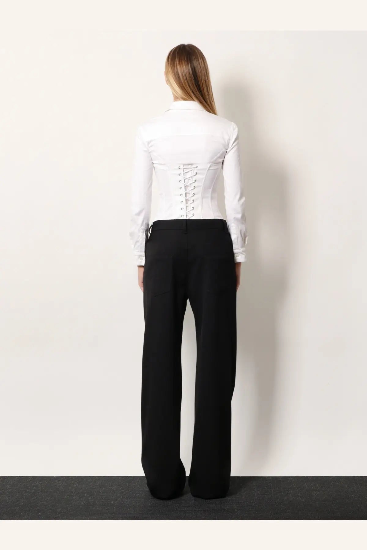 White corset-style blouse with lace-up back and long sleeves paired with Balenciaga black stretch wool trousers