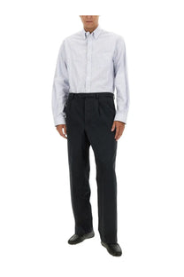 A man wearing Bally men’s black cotton pants paired with a light blue and white striped long-sleeved shirt