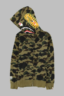 A bathing ape men’s olive green camouflage zip-up hoodie with bold yellow and black shark face on the hood