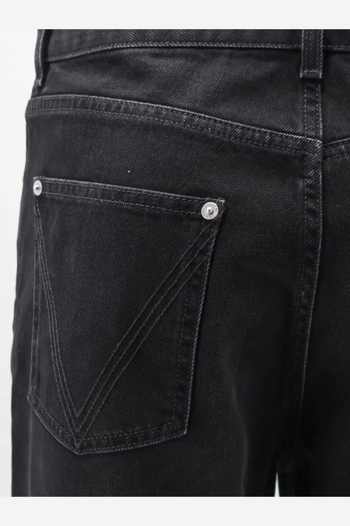 Back side of bottega veneta men’s black denim trousers showing classic back pocket with silver button fastenings