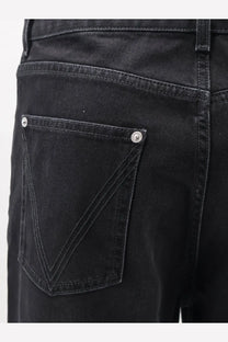 Back side of bottega veneta men’s black denim trousers showing classic back pocket with silver button fastenings