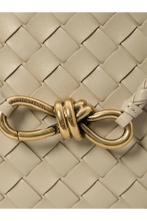 A gold tone metal clasp with knotted design engraved with bottega veneta on a light beige woven leather strap of bottega veneta womens andiamo leather shoulder bag white