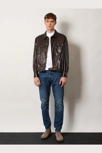 Brown leather jacket with two front flap pockets and button closures paired with brunello cucinelli men’s white cotton shirt