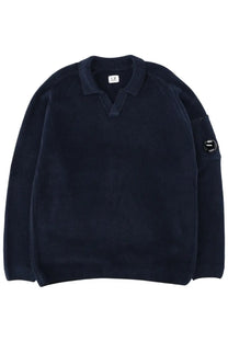 Dark navy blue cotton knit polo sweater by c.p. company with ribbed collar cuffs and a logo patch on the left sleeve