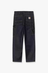 Dark indigo denim work pants with contrasting light stitching and carhartt logo patch on back right pocket showing back side