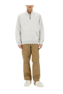 Light gray carhartt half zip sweatshirt with ribbed cuffs and hem paired with beige cargo pants for men