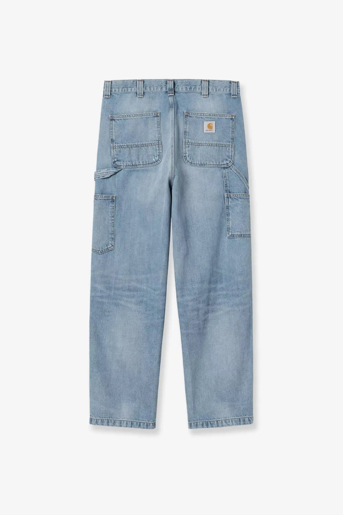 Back side of light-wash denim work pants with multiple pockets and carhartt logo patch on the back right pocket