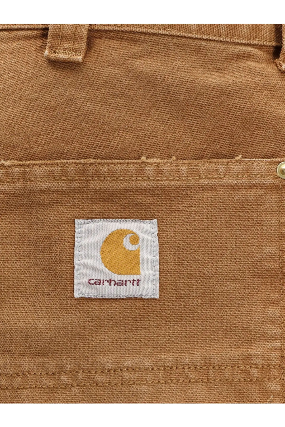 Tan canvas pocket of carhartt wip men’s organic cotton shorts brown featuring white label with yellow logo and name