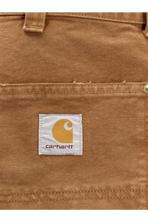 Tan canvas pocket of carhartt wip men’s organic cotton shorts brown featuring white label with yellow logo and name