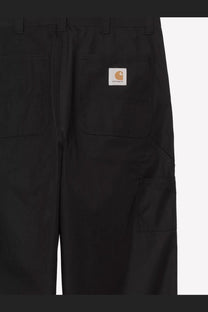 Black carhartt wip men’s postal single knee cotton blend trousers with durable fabric and orange logo patch back side