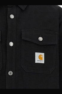 Black Carhartt Wip men’s Selby cotton work shirt jacket with silver buttons and white patch featuring orange logo