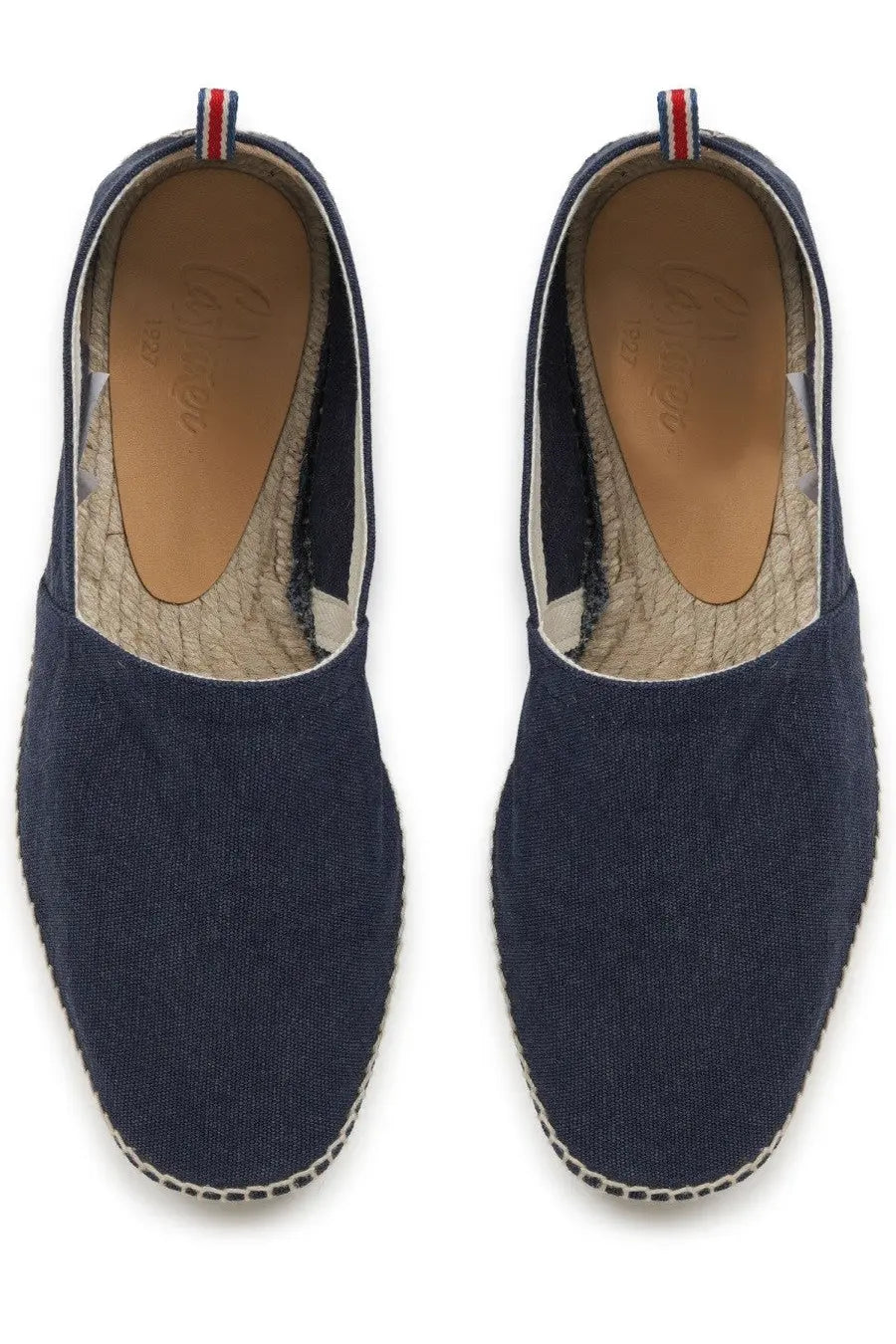 Navy blue canvas espadrilles with woven jute sole and red white blue striped pull tab at the heel by castañer