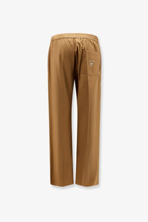 Back side of celine men’s cotton and linen tan satin trousers with subtle sheen elastic waistband and embroidered logo