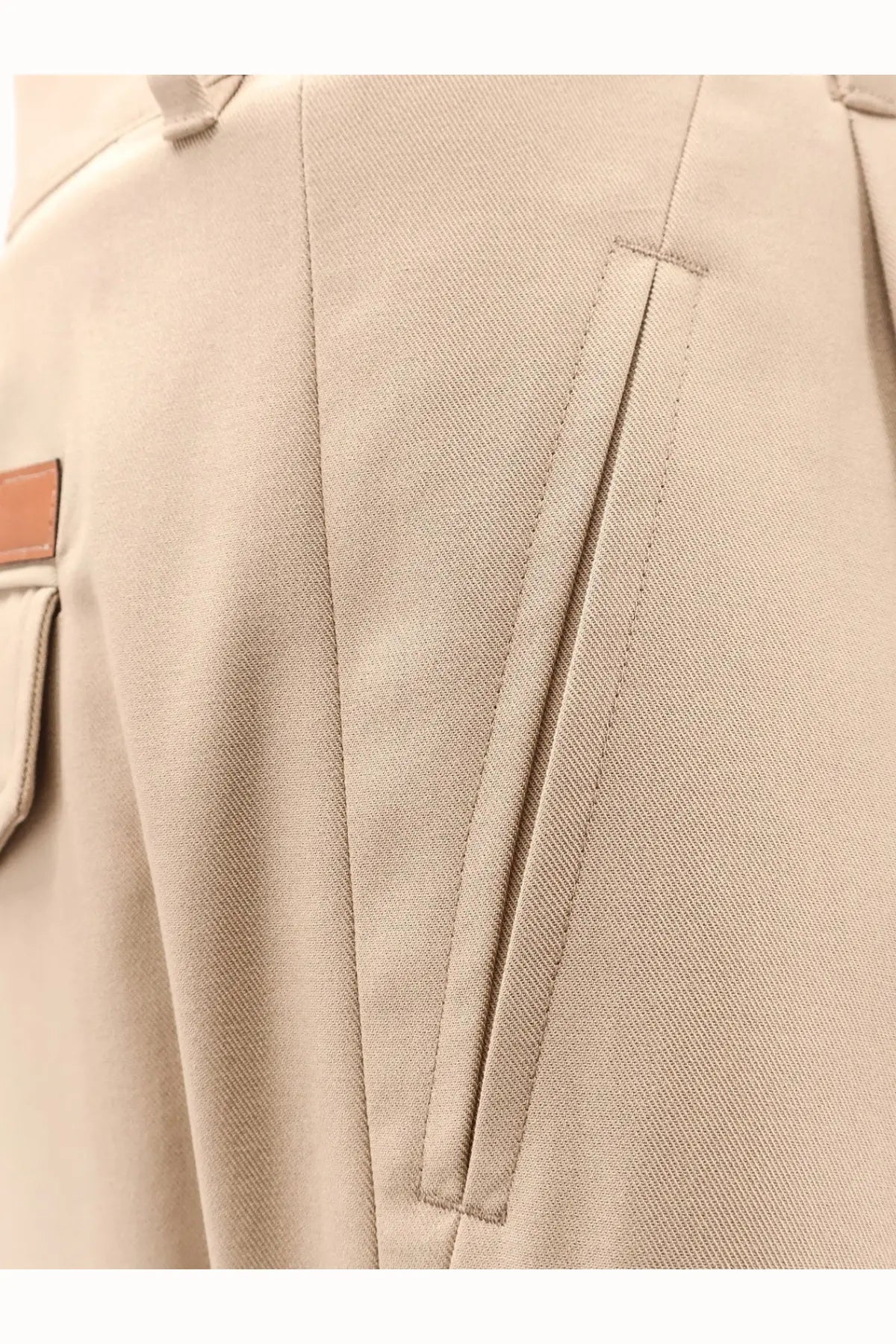 Beige cotton celine men’s trousers with textured fabric, subtle vertical seam, and small brown leather side patch