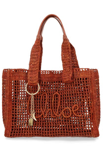 A woven rust-colored chloé womens borsa tote bag with braided handles and gold-tone keychain charm