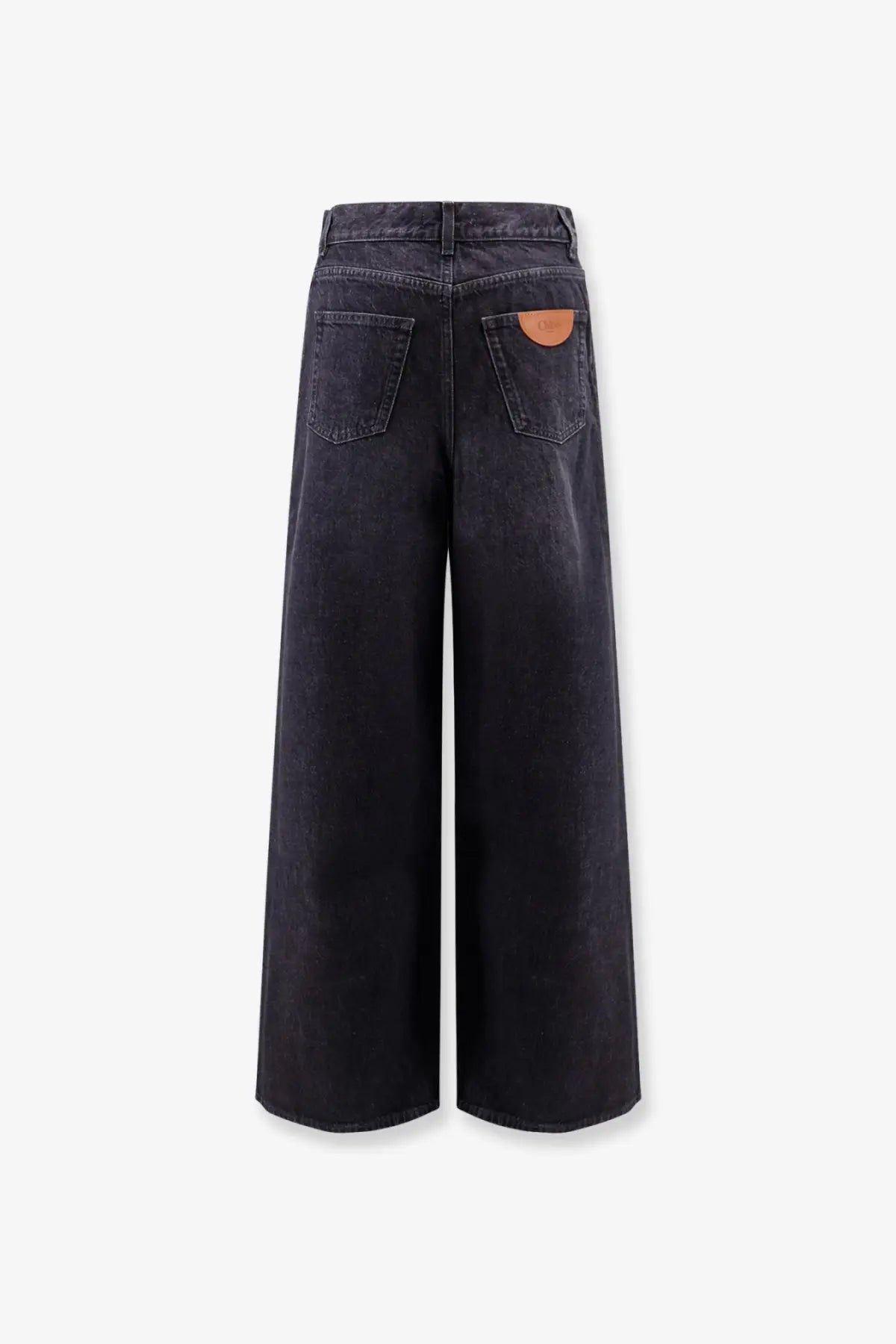 Back side of chloé women’s dark-wash denim wide-leg jeans with a brown leather patch on the pocket