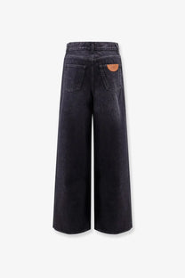 Back side of chloé women’s dark-wash denim wide-leg jeans with a brown leather patch on the pocket