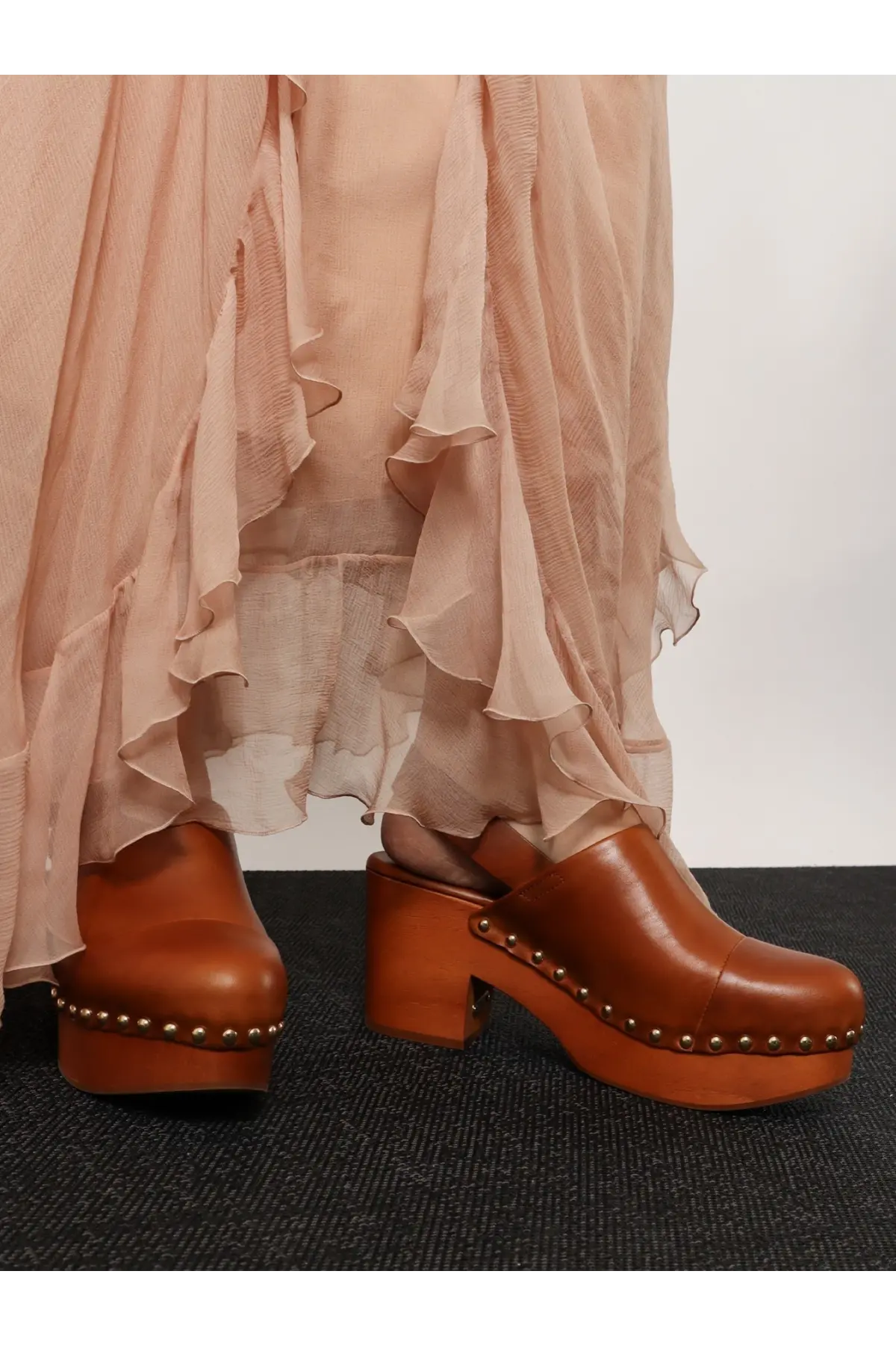 Brown leather clog shoes with chunky wooden heel and metallic studs along sole from chloé jeanette sabot collection