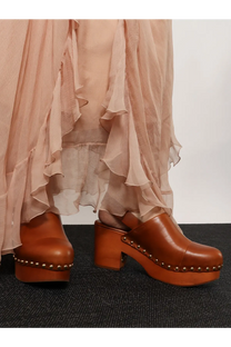 Brown leather clog shoes with chunky wooden heel and metallic studs along sole from chloé jeanette sabot collection